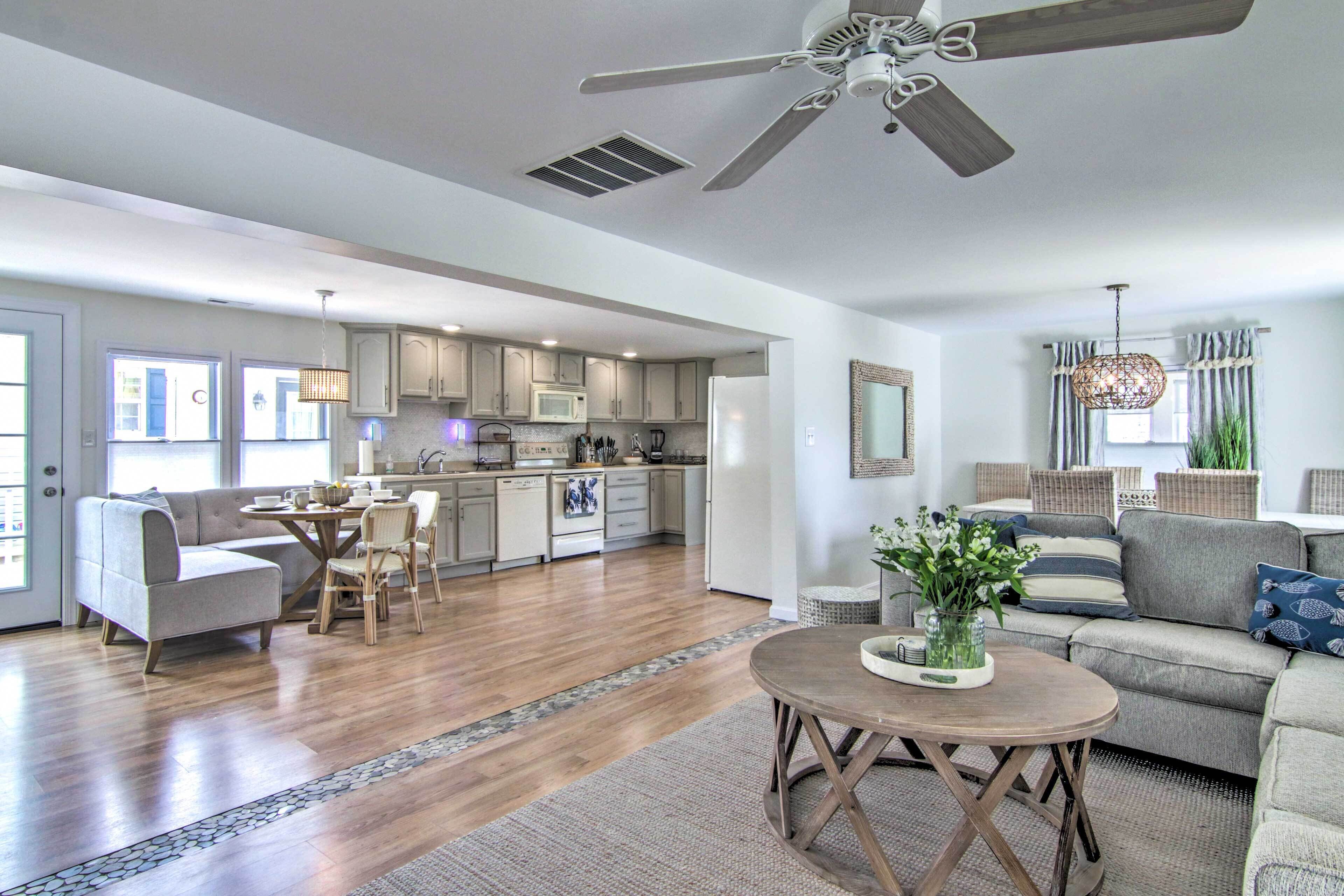 A spacious living area with a dining table, sofas, and a kitchen in the background.