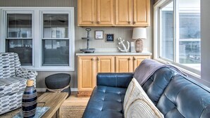 A cozy living room with a blue sofa, a patterned armchair, and a small table with a decorative vase. - Fire Pit + Views: Canal-front Fenwick Island Home (Selbyville)