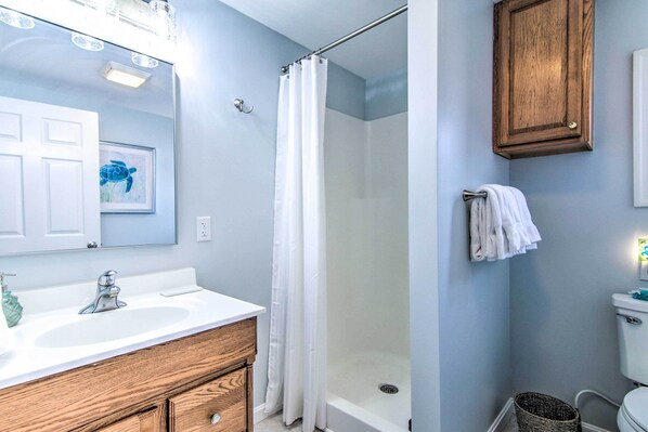 Un baño con ducha, lavabo y armario de madera.