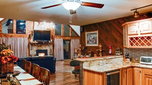 A spacious living room with a fireplace, a dining area with a wooden table and chairs, and a kitchen with wooden cabinets and a granite countertop. - Lake Harmony Vacation Rental w/ Hot Tub & Views! (Lake Harmony)