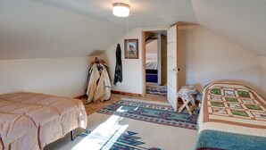 Een slaapkamer met een bed, een kledingkast, een kapstok en een deur naar een andere kamer.