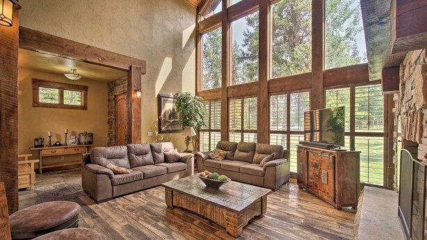 Un salón amplio con ventanas grandes, muebles de madera y una chimenea de piedra.