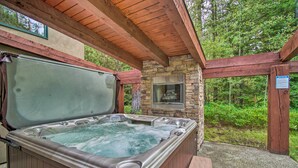 Un jacuzzi con un fondo de pared de piedra, vigas de madera y una chimenea de piedra.