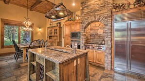 Una cocina con chimenea de piedra, encimeras de granito, armarios de madera y electrodomésticos de acero inoxidable.
