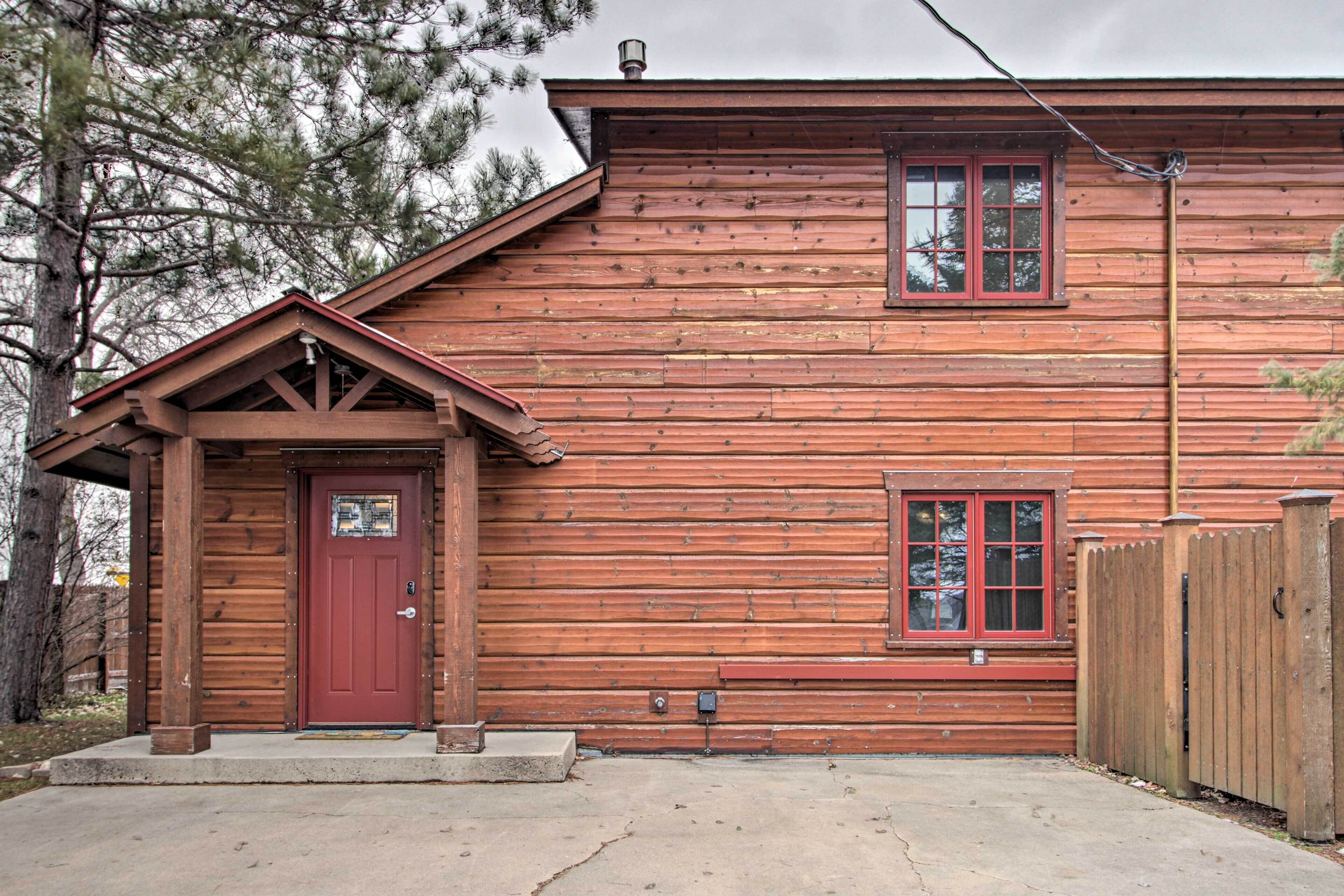A wooden cabin with a red door, a small porch, and a window.