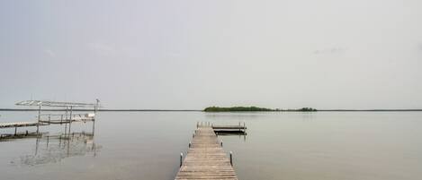 Un muelle de madera que se extiende sobre aguas tranquilas, con una pequeña isla a lo lejos.