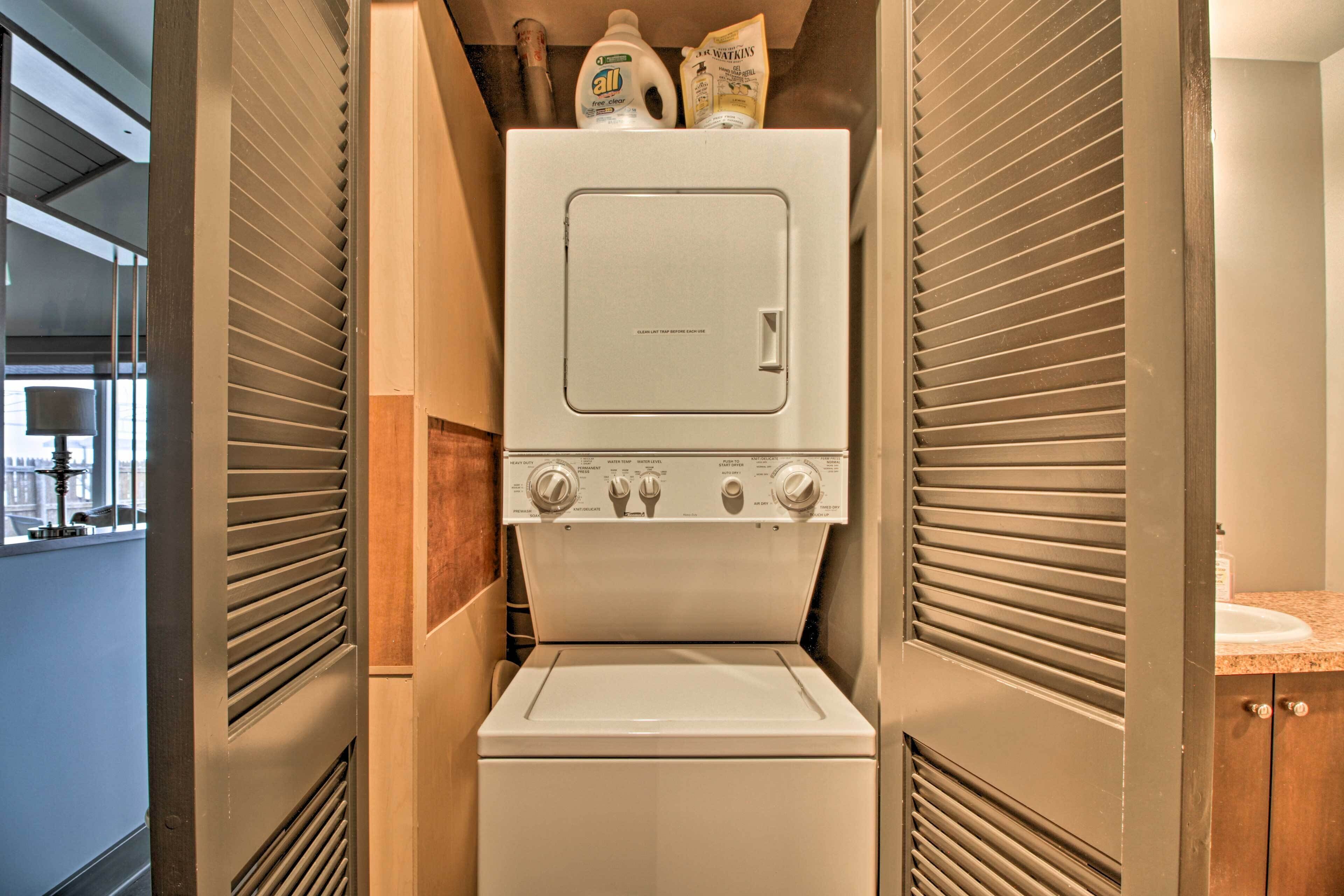 A compact laundry room with a washer and dryer, a window, and a countertop with a sink.