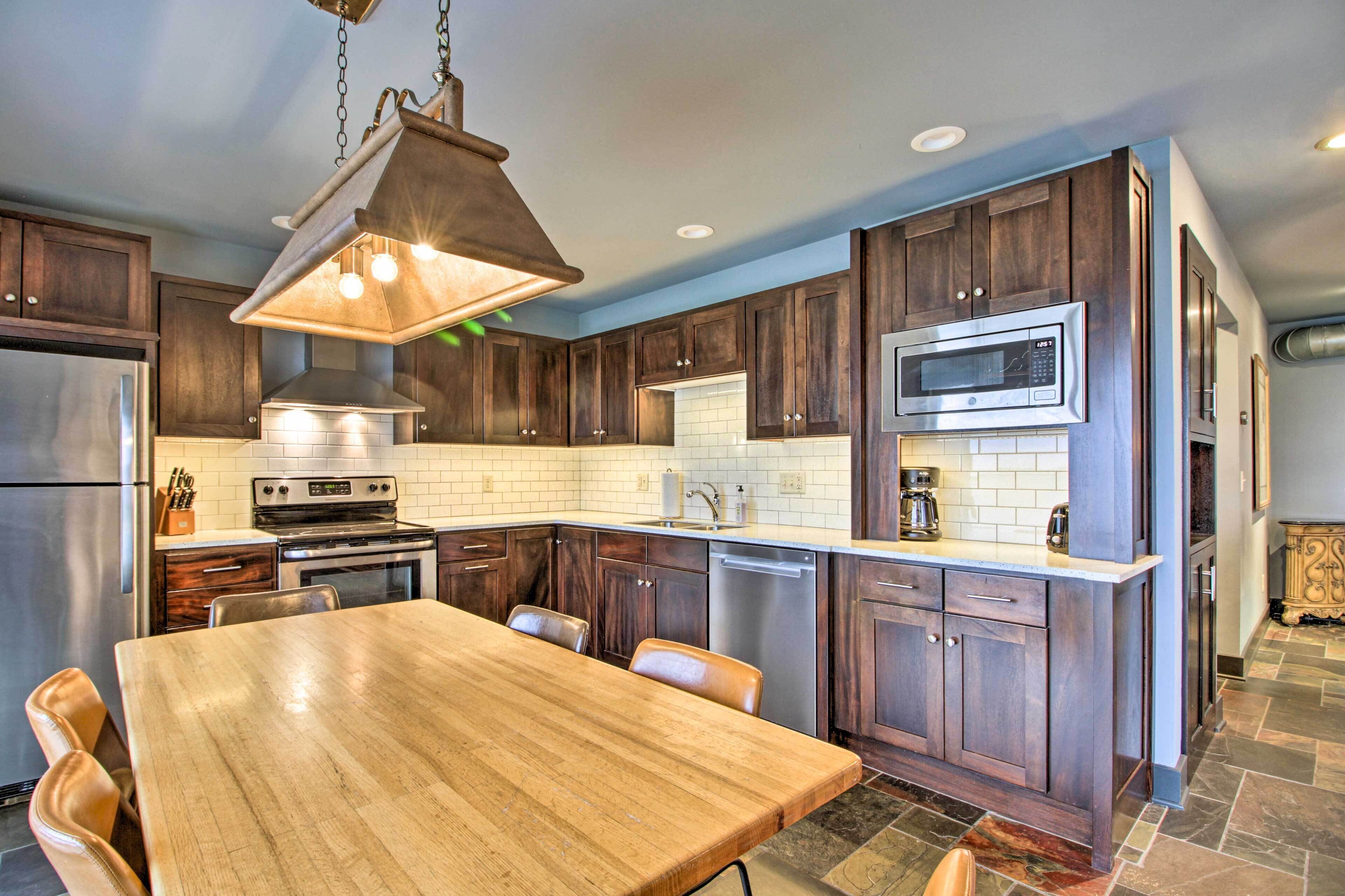 A modern kitchen with dark wood cabinets, stainless steel appliances, and a wooden dining table.