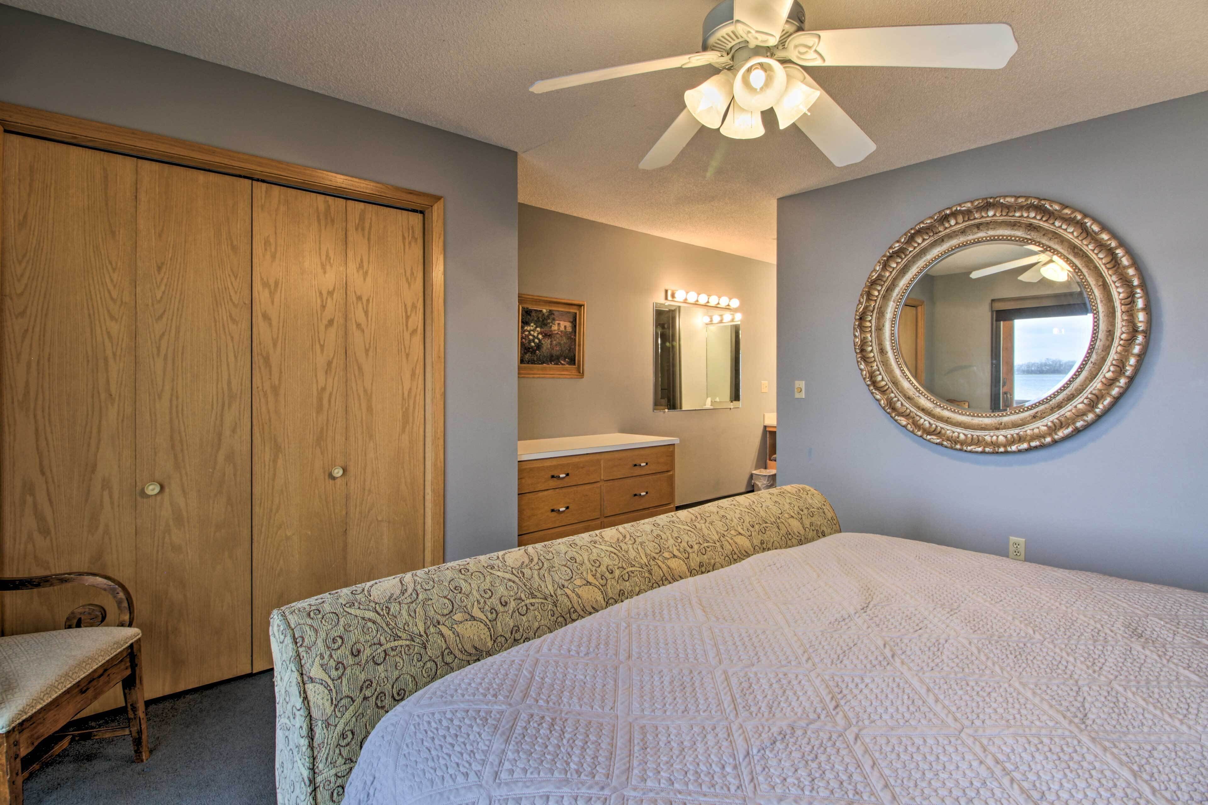 A bedroom with a bed, a vanity with a mirror, a ceiling fan, and a wardrobe.