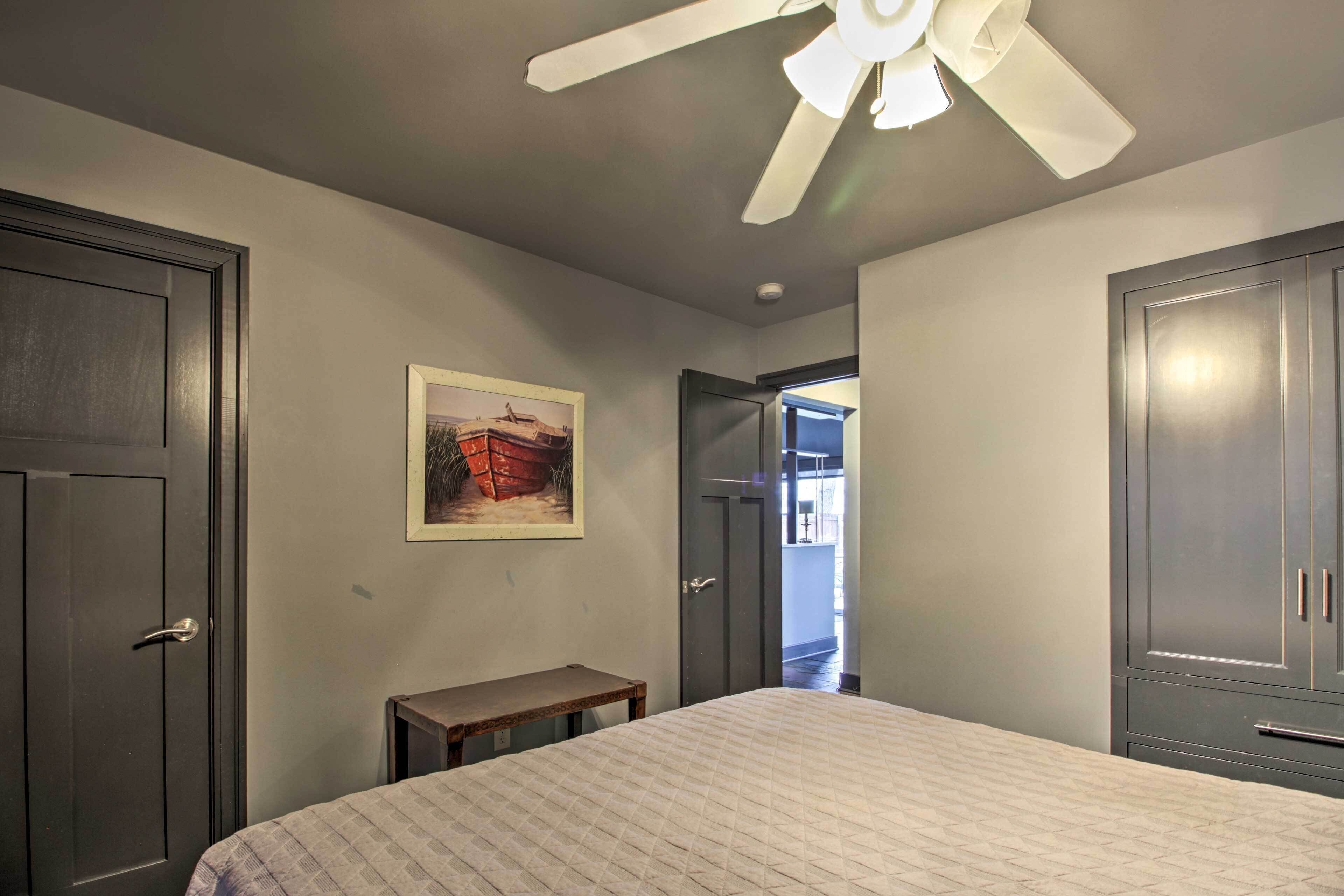 Une chambre à coucher avec un lit, un ventilateur de plafond, une porte et une petite table.