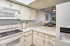 A modern kitchen with white cabinetry, a built-in microwave, a stove, and a refrigerator. - Las Vegas Condo: Explore The Strip & Downtown (Las Vegas)