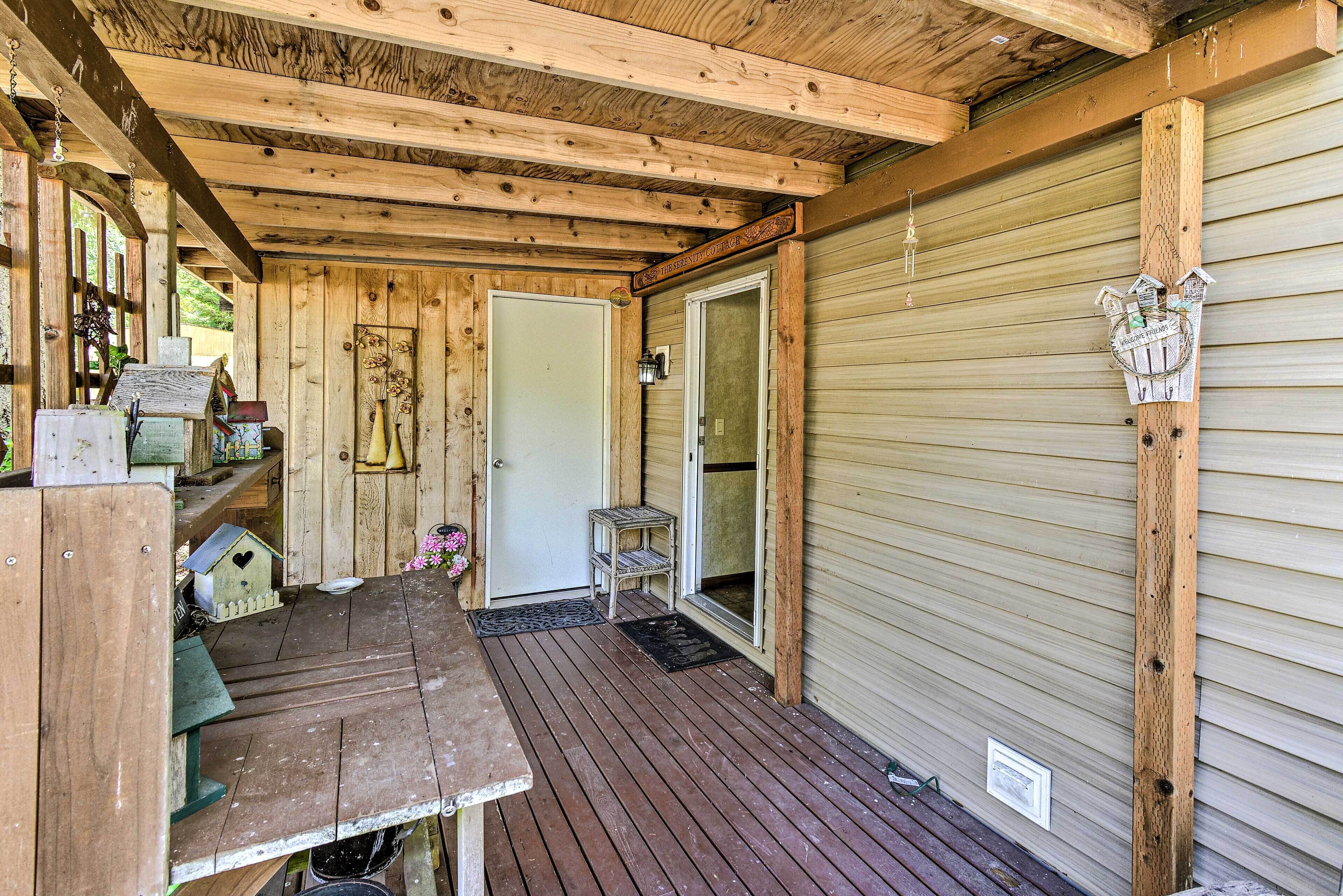 A wooden deck with a bench, a small table, and a birdhouse.