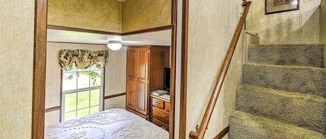 A bedroom with a bed, a dresser, a window, and a staircase.