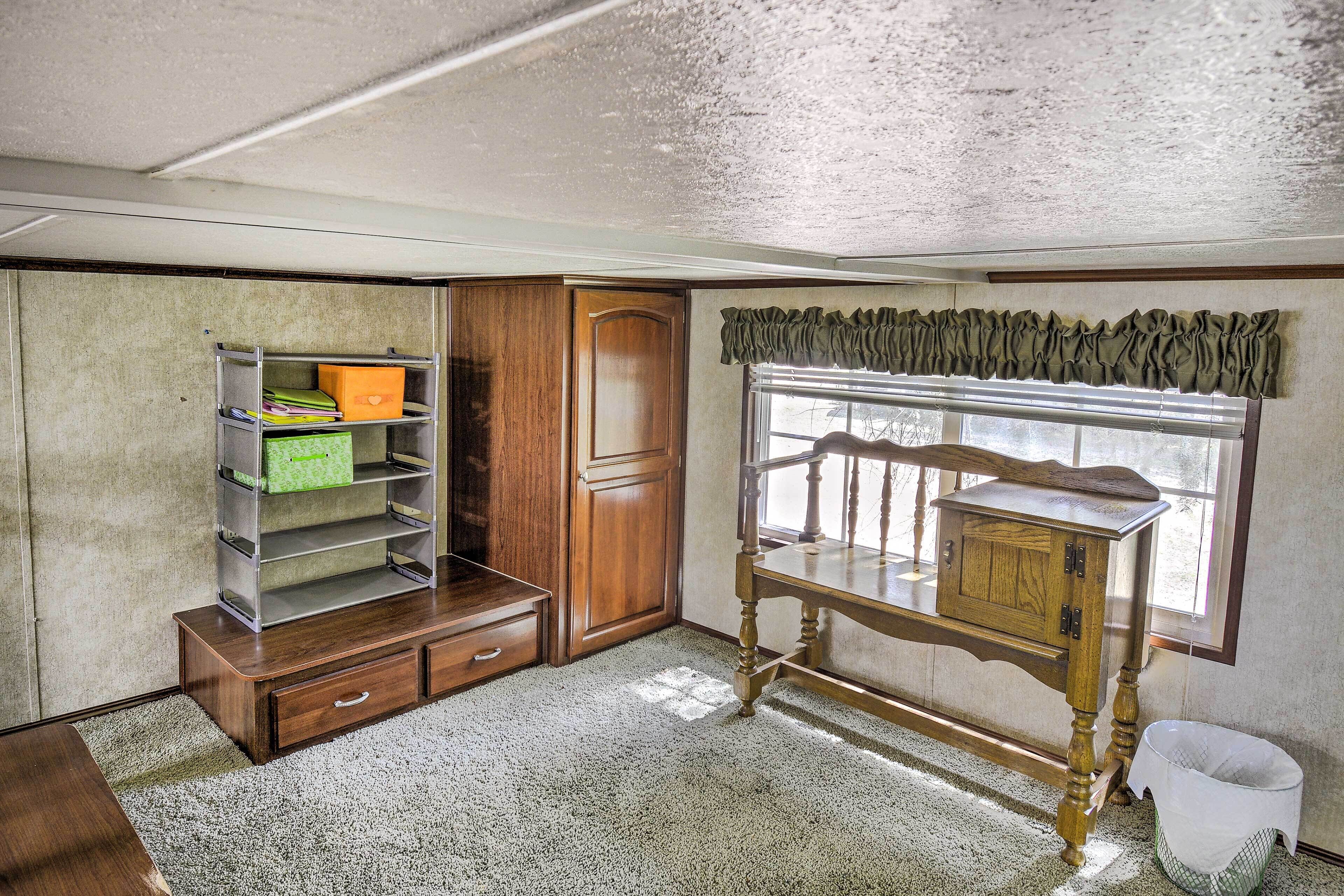 A room with a wooden desk, a window with a valance, a bookshelf, and a door.