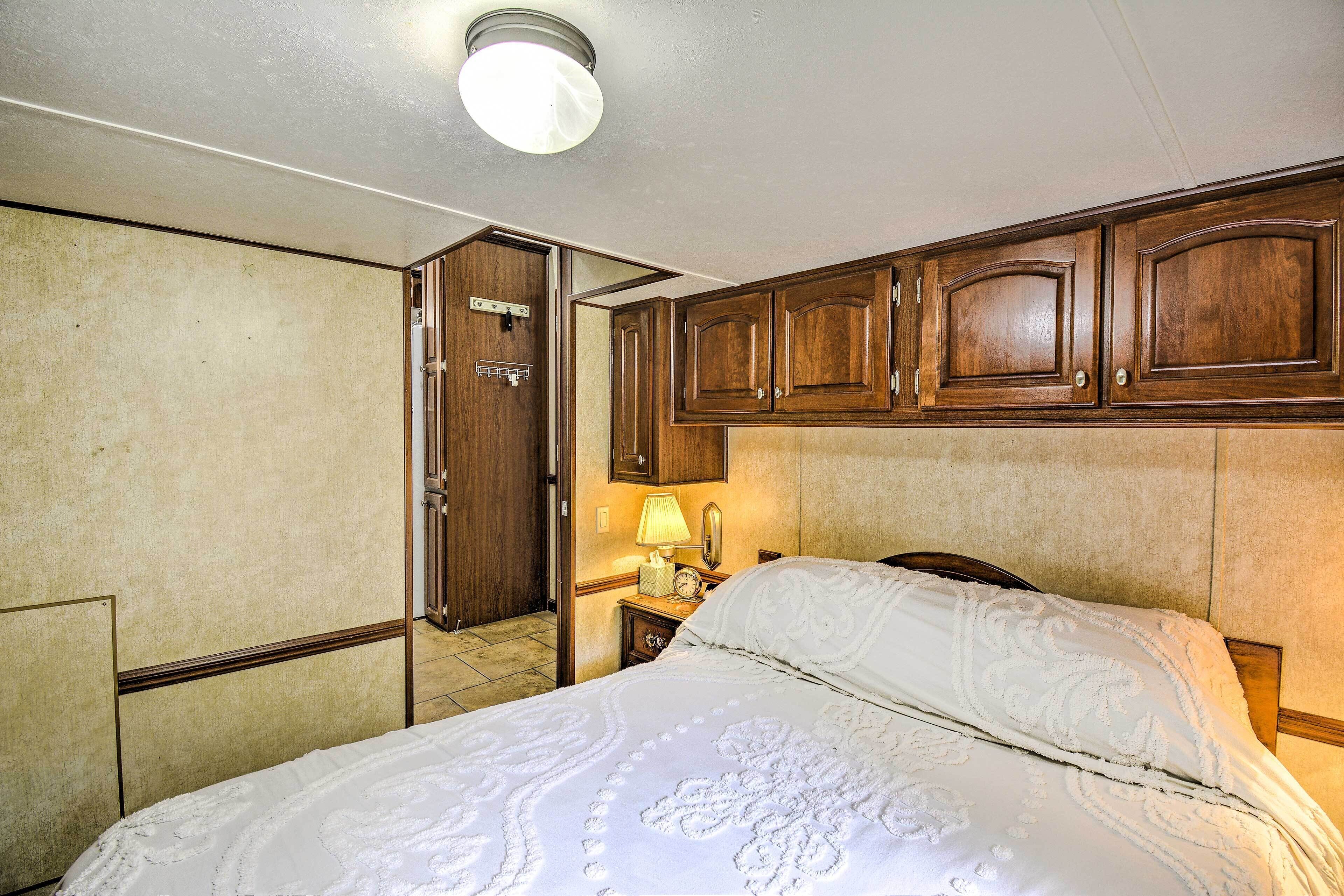A bedroom with a bed, wooden cabinets, a nightstand, and a lamp.