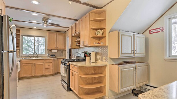 A modern kitchen with wooden cabinets, a built-in stove, and a ceiling fan. - Large Greeley House w/ 2 Game Rooms + Yard! (Greeley)