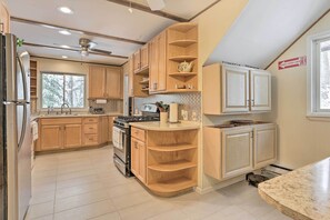 A modern kitchen with wooden cabinets, a built-in stove, and a ceiling fan.