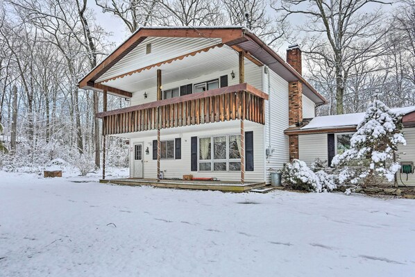 A two-story house with a balcony, surrounded by snow-covered trees. - Large Greeley House w/ 2 Game Rooms + Yard! (Greeley)