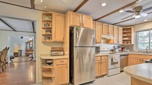 A modern kitchen with wooden cabinets, a stainless steel refrigerator, and a built-in oven. - Large Greeley House w/ 2 Game Rooms + Yard! (Greeley)