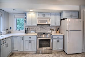A modern kitchen with light blue cabinets, a stainless steel oven, a microwave, and a white refrigerator. - Lakefront Family Retreat: Skiing & Mountain Biking (Greenwood)