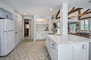 A modern kitchen with white cabinetry, a central island, and a hexagonal tile floor. - Lakefront Family Retreat: Skiing & Mountain Biking (Greenwood)