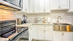 Una cocina moderna con gabinetes blancos, electrodomésticos de acero inoxidable y una encimera de granito.