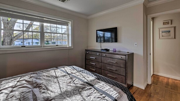 A bedroom with a bed, dresser, TV, and window. - Luxury Hamptons Home on Canal w/ Dock & Kayaks! (East Quogue)