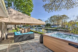 Un patio con un jacuzzi, mobiliario exterior y una zona cubierta.