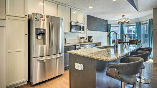 A modern kitchen with stainless steel appliances, a granite countertop, and bar stools. - Idyllic Pinehurst Home, Near Golf Course! (Pinehurst)