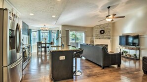 A spacious kitchen with a central island, a dining area with chairs, a built-in oven, and a large TV on a stand. - Idyllic Pinehurst Home, Near Golf Course! (Pinehurst)