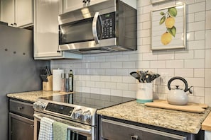 A modern kitchen with stainless steel appliances, granite countertops, and a tiled backsplash.