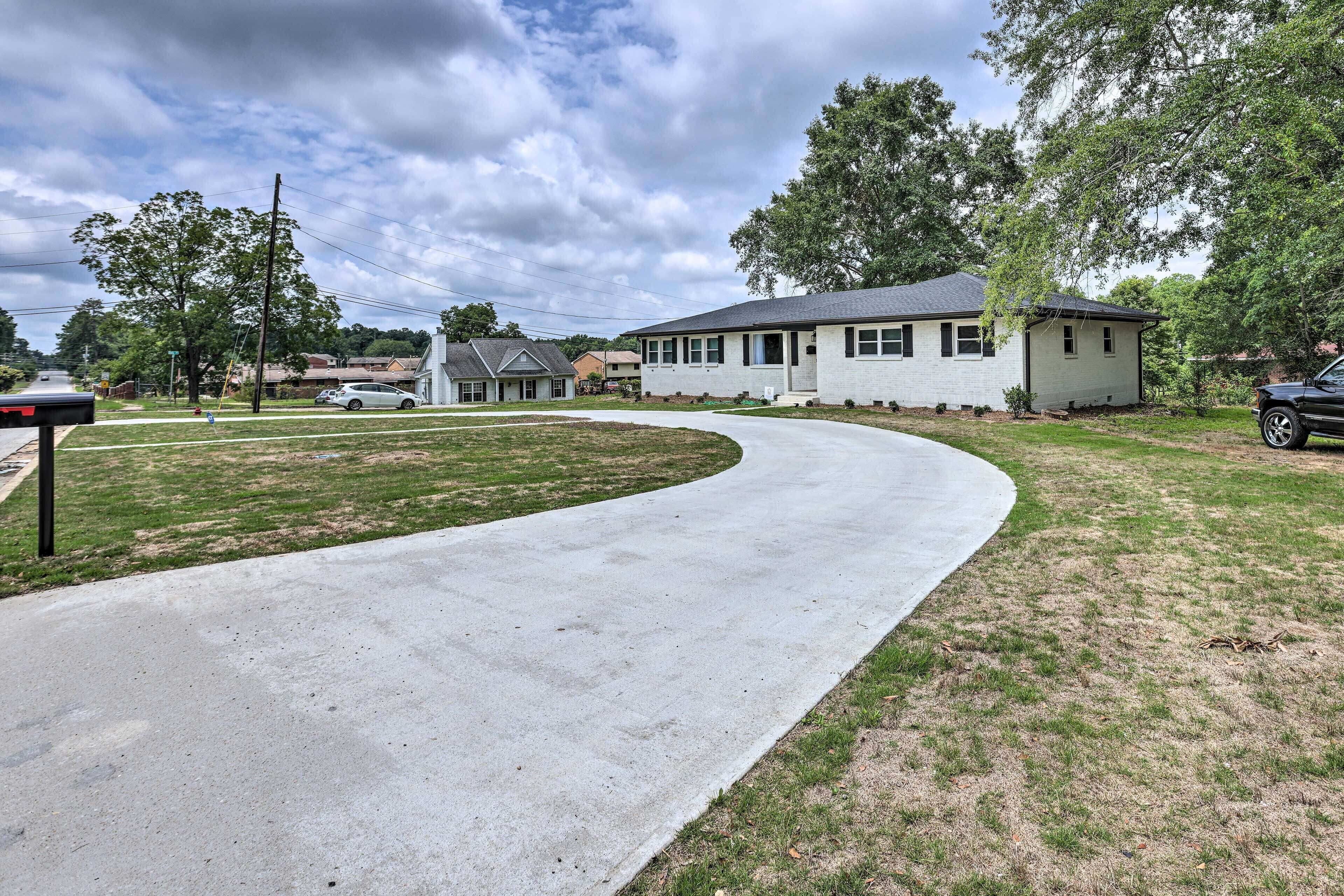 A residential area with a curved driveway leading to a house with a white exterior and a dark roof.