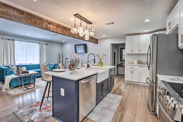 A modern kitchen with a central island, stainless steel appliances, and a dining area with a blue sofa and a small table.