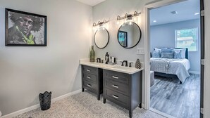 A bathroom with a double sink vanity, two round mirrors, and a framed artwork on the wall. - Modern, Colorful Home ~ 2 Mi to Tuskegee Uni (Tuskegee)
