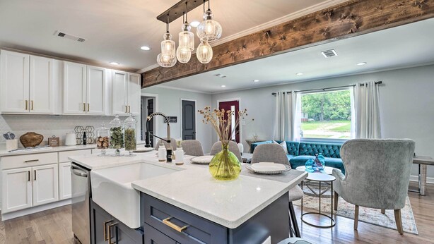 A modern kitchen with white cabinets, a central island, and a dining area with a blue sofa and grey armchairs. - Modern, Colorful Home ~ 2 Mi to Tuskegee Uni (Tuskegee)