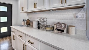 A kitchen with white cabinets, a speckled countertop, and a hexagonal tile backsplash. - Modern, Colorful Home ~ 2 Mi to Tuskegee Uni (Tuskegee)