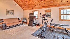 Una habitación con techo de madera, sofá de cuero, cinta de correr y bicicleta estática.