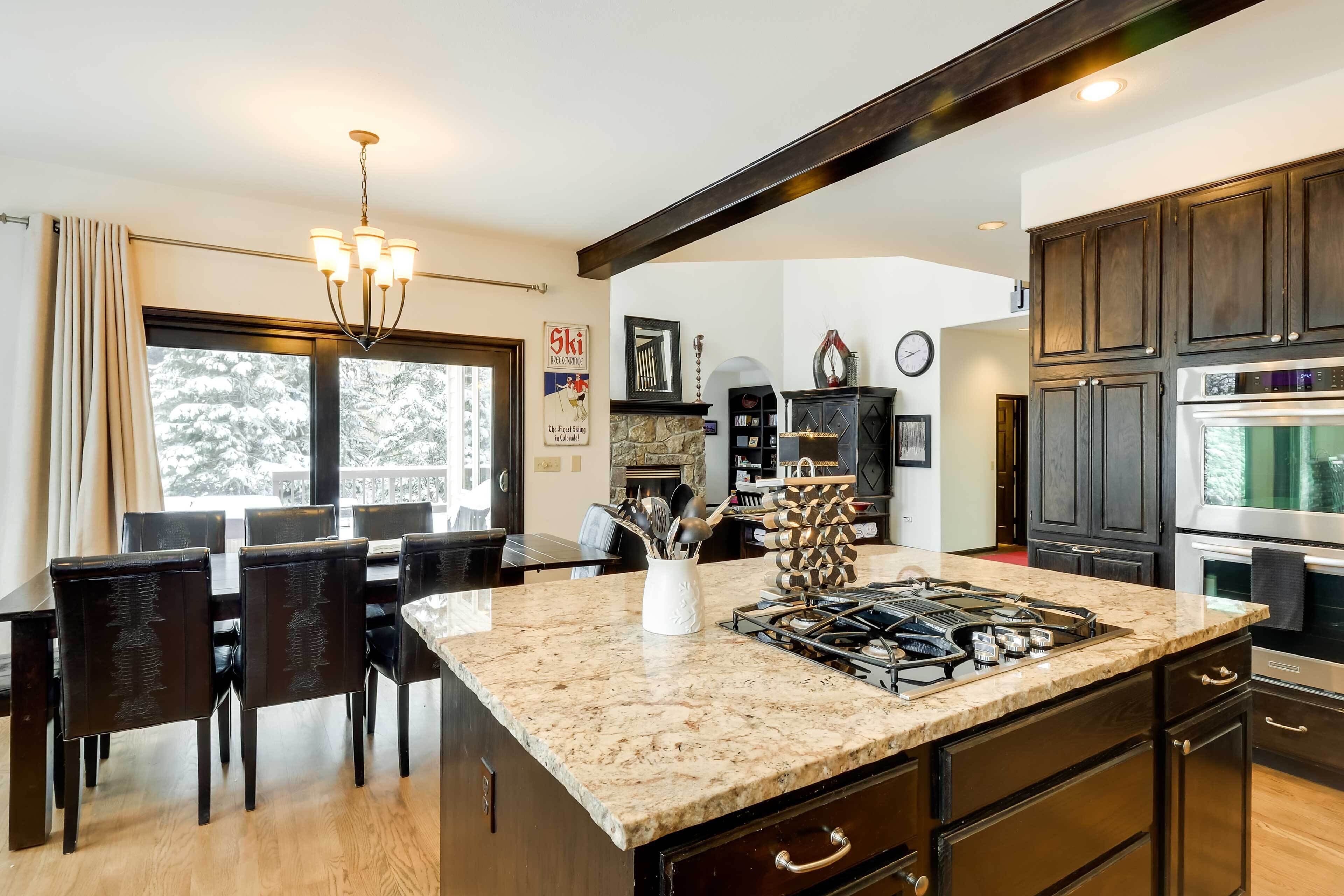 A modern kitchen with dark wood cabinets, a granite countertop, and a gas stove.