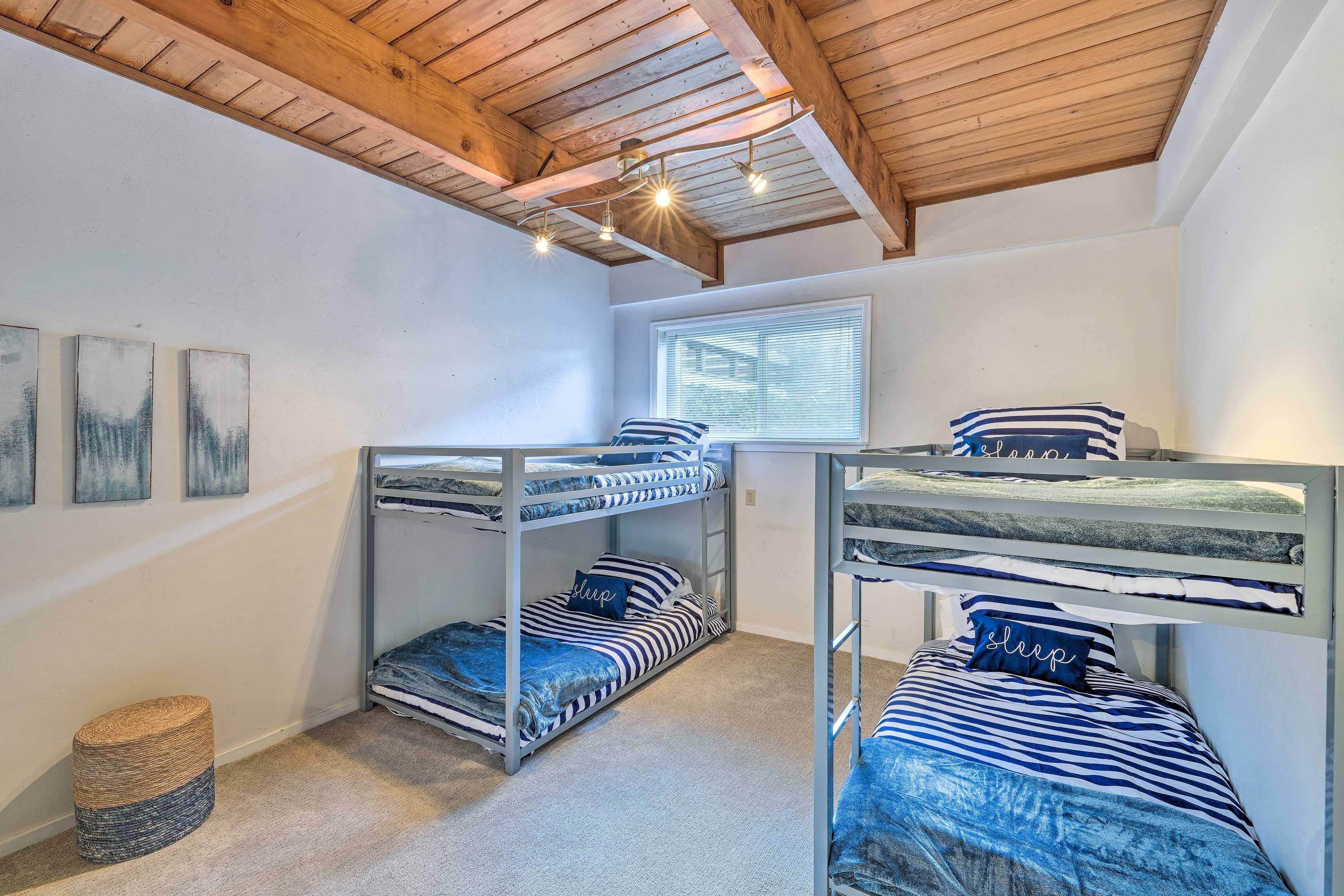 A bunk bed room with a wooden ceiling, a window with blinds, and a small round wicker basket.