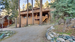 A cabin with a gravel driveway, wooden deck, and a staircase leading to the upper level. - Peaceful & Idyllic Forest Cabin w/ Pool Table (Pine Mountain Club)