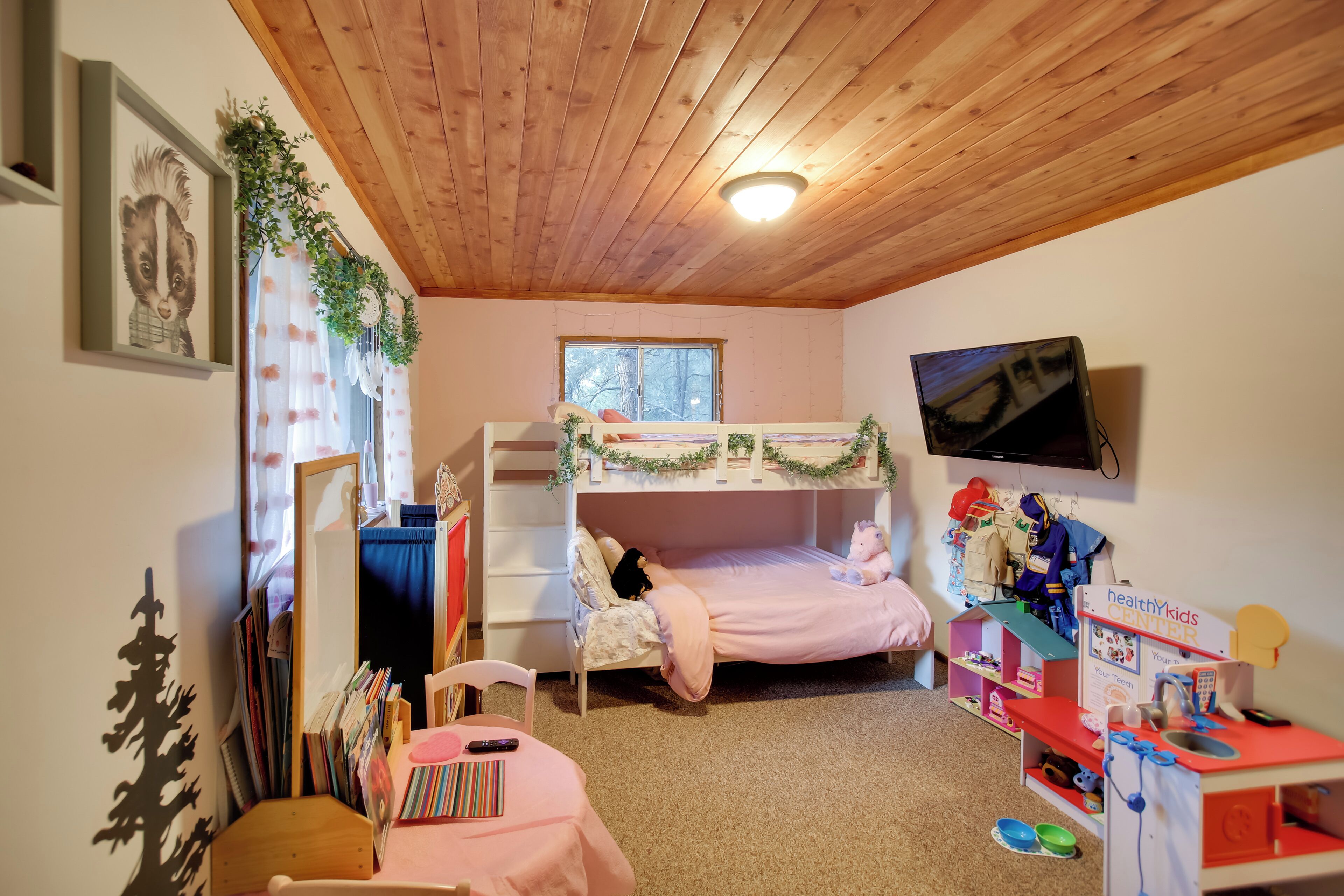 Une chambre d’enfant avec des lits superposés, un bureau, un miroir et un espace de jeux.