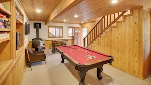 A wooden interior with a pool table, a fireplace, and a staircase. - Peaceful & Idyllic Forest Cabin w/ Pool Table (Pine Mountain Club)