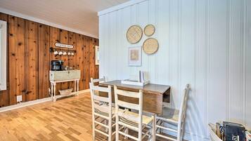 A dining area with a wooden table and chairs, a coffee bar, and wall-mounted woven baskets.