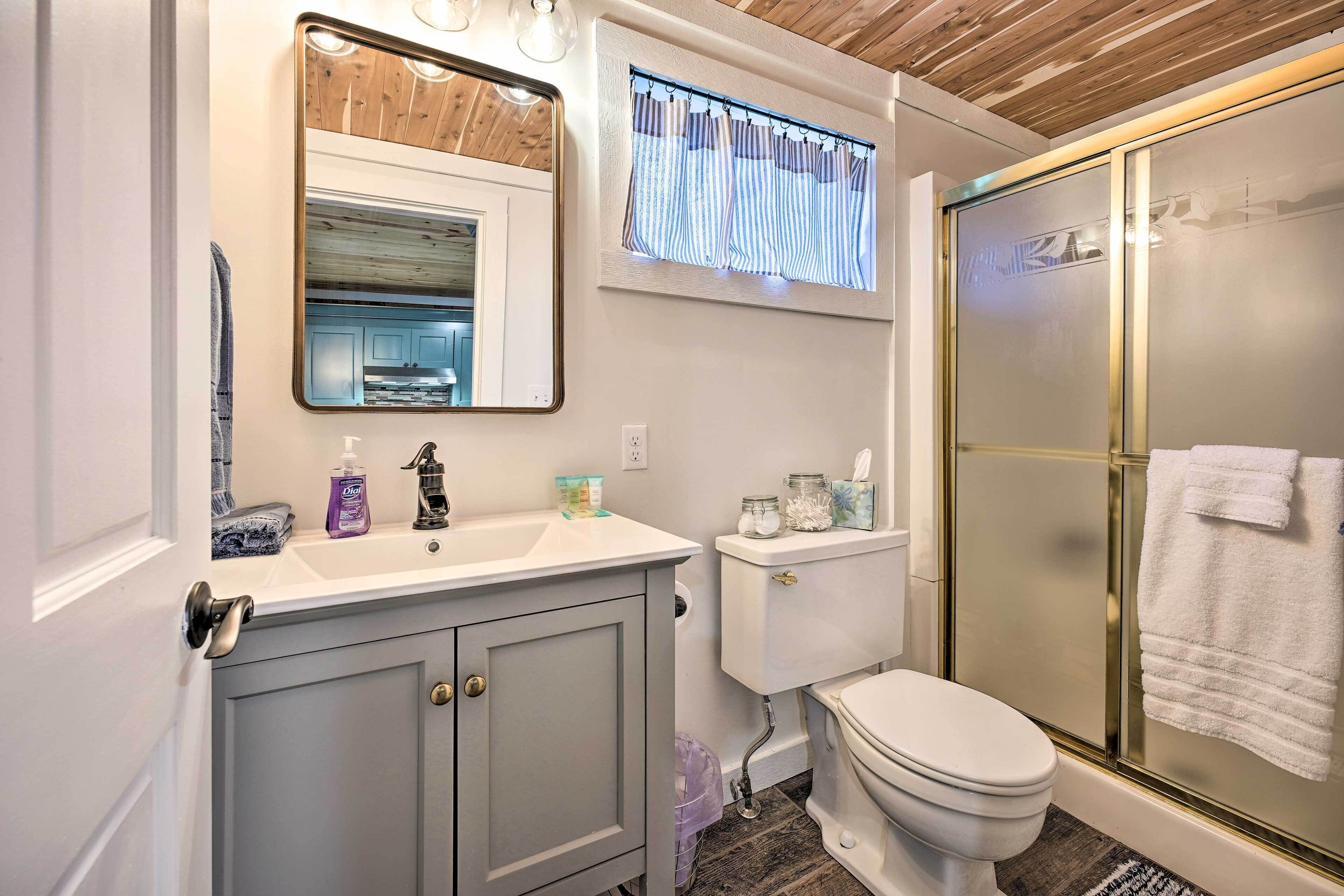 A bathroom with a toilet, sink, mirror, and shower.