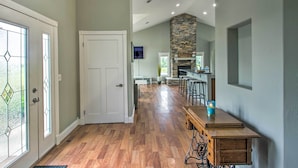 A spacious kitchen with a stone fireplace, wooden bar, and a long dining table. - Quiet Retreat w/ Kayak & Patio, Walk to Lake! (Audubon)