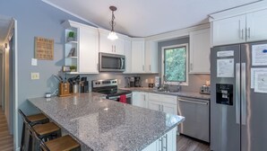 A modern kitchen with granite countertops, stainless steel appliances, and bar stools. - Lake Harmony Estates Family Home w/ Beach Access (Lake Harmony)