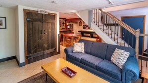 A living room with a blue sofa, wooden coffee table, and a laundry sign on a door. - Lake Harmony Estates Family Home w/ Beach Access (Lake Harmony)