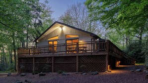 A cabin with a wooden deck and a large window, surrounded by trees. - Lake Harmony Estates Family Home w/ Beach Access (Lake Harmony)