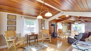 A cozy cabin interior with wooden floors, rocking chairs, a fireplace, and a dining area. - Cozy Lake Champlain Cottage w/ Private Beach! (North Hero)