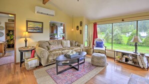 A cozy living room with a sofa, coffee table, and a large window offering a view of the outdoors.